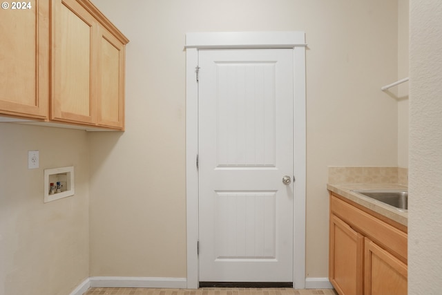 clothes washing area with cabinets, sink, and washer hookup