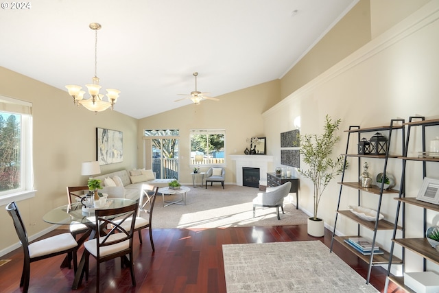 living room featuring dark hardwood / wood-style floors, ceiling fan with notable chandelier, a healthy amount of sunlight, and vaulted ceiling