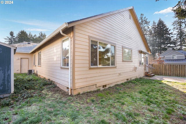 view of side of home featuring a yard and central AC unit