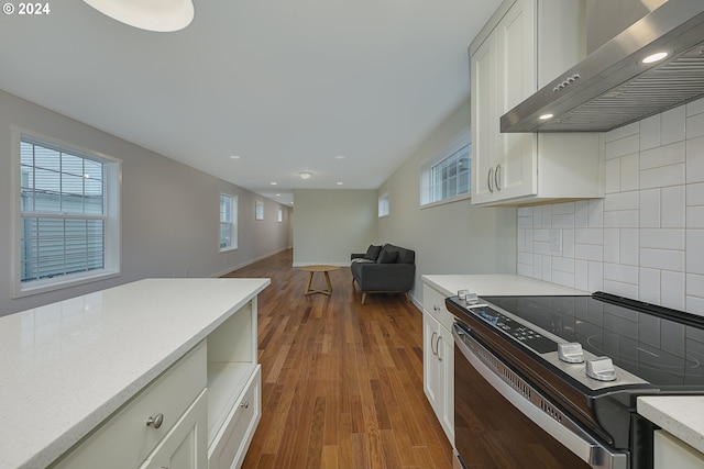 kitchen featuring a wealth of natural light, electric range, dark hardwood / wood-style flooring, and wall chimney exhaust hood