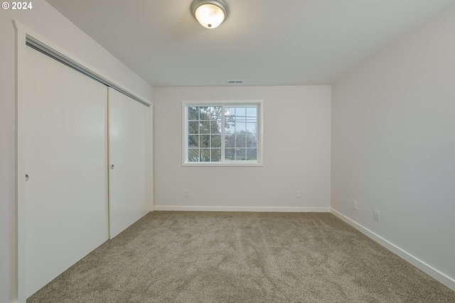 unfurnished bedroom featuring light carpet and a closet