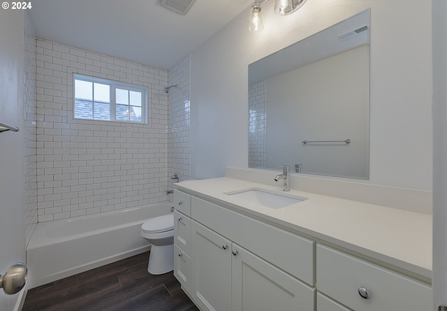 full bathroom featuring hardwood / wood-style floors, vanity, toilet, and tiled shower / bath