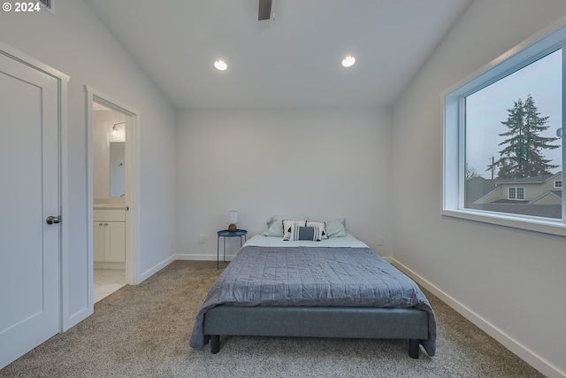 carpeted bedroom with ensuite bathroom and vaulted ceiling