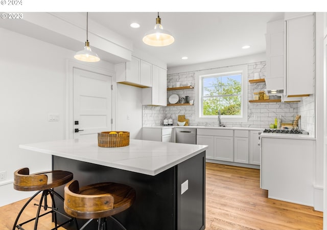 kitchen with backsplash, a kitchen island, light hardwood / wood-style floors, dishwasher, and white cabinetry