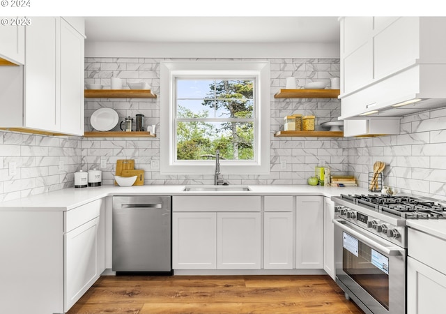 kitchen with gas stove, white cabinets, sink, light hardwood / wood-style floors, and stainless steel dishwasher