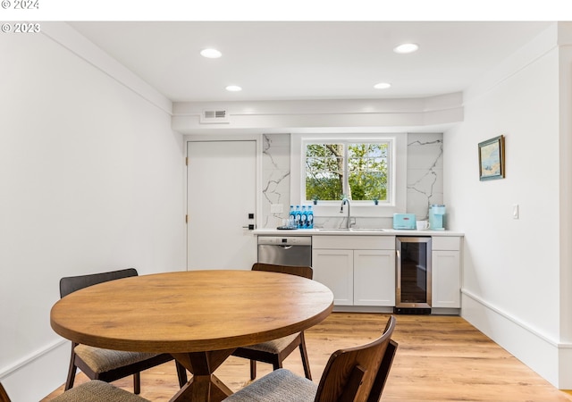 dining area featuring beverage cooler, sink, and light wood-type flooring