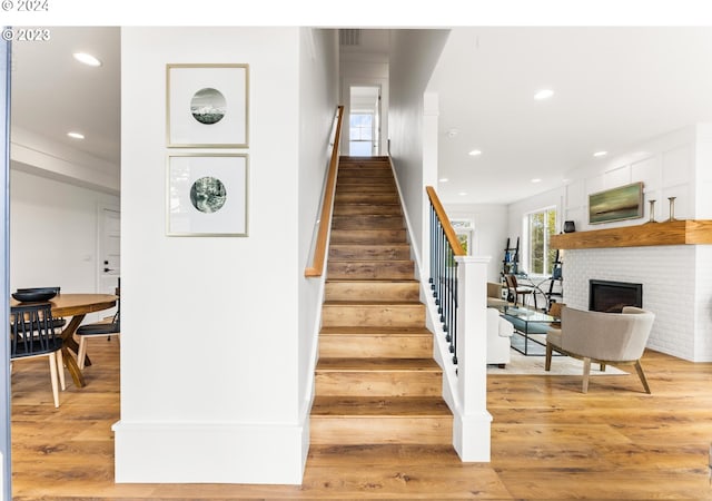 staircase with hardwood / wood-style floors and a fireplace