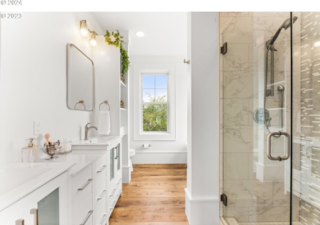 bathroom with hardwood / wood-style floors, an enclosed shower, toilet, and dual vanity