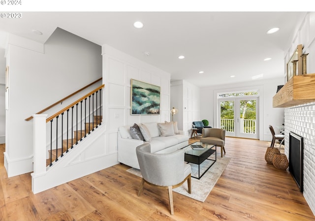 living room featuring french doors, light wood-type flooring, and a fireplace