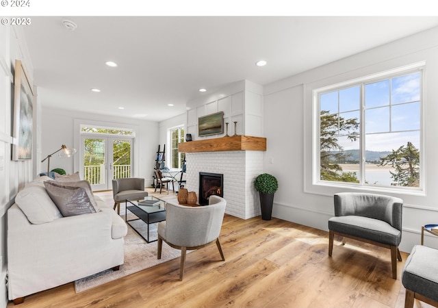 living room with a fireplace, french doors, and light hardwood / wood-style floors