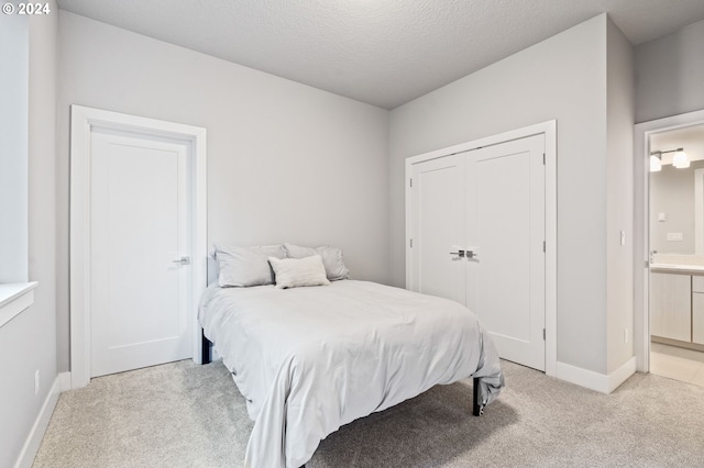 carpeted bedroom featuring ensuite bathroom, a textured ceiling, and a closet