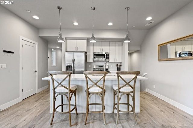 kitchen featuring white cabinets, light hardwood / wood-style floors, hanging light fixtures, and appliances with stainless steel finishes