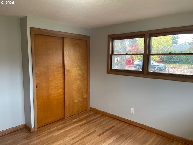 unfurnished bedroom featuring a closet, a textured ceiling, and light hardwood / wood-style flooring