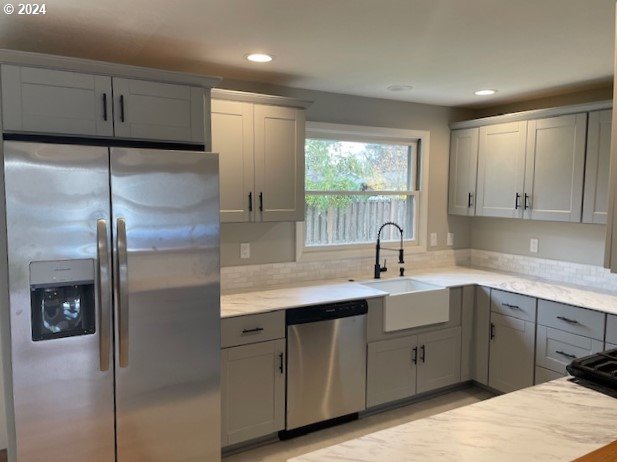 kitchen with decorative backsplash, gray cabinets, sink, and stainless steel appliances