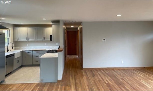 kitchen featuring gray cabinetry, sink, light hardwood / wood-style floors, and appliances with stainless steel finishes