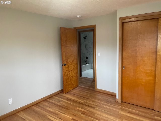 unfurnished bedroom with a textured ceiling, light hardwood / wood-style flooring, and a closet