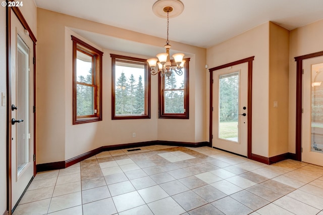 tiled spare room with an inviting chandelier