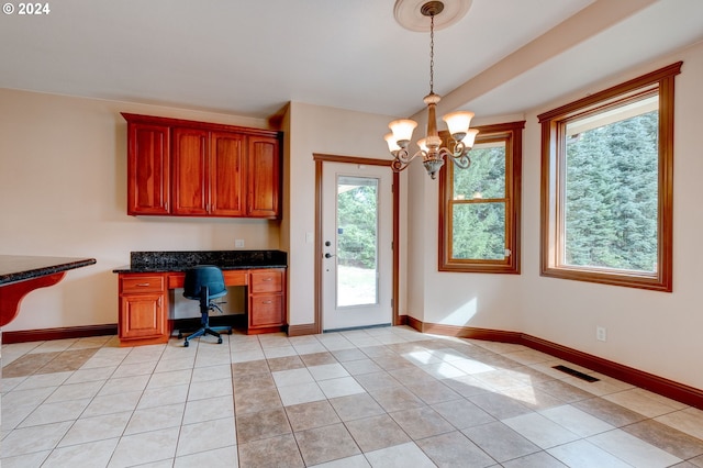 unfurnished office with built in desk, light tile patterned floors, and a chandelier