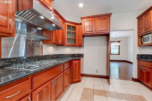 kitchen featuring range hood, white microwave, light hardwood / wood-style floors, and dark stone counters