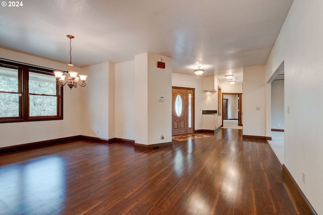 empty room with an inviting chandelier, dark hardwood / wood-style flooring, and a textured ceiling