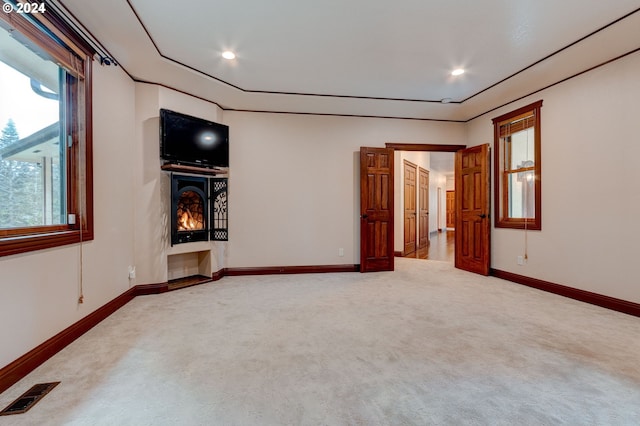 unfurnished room featuring a fireplace, light carpet, and plenty of natural light