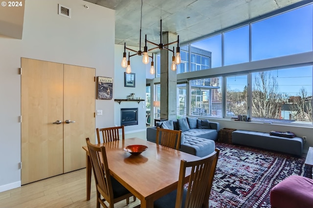 dining space featuring a towering ceiling and light hardwood / wood-style floors