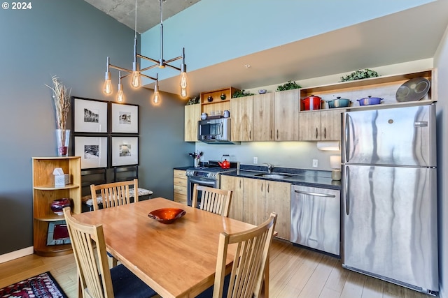 kitchen with sink, decorative light fixtures, light brown cabinetry, appliances with stainless steel finishes, and light wood-type flooring