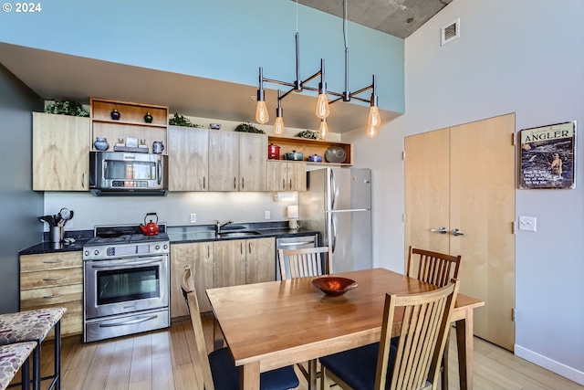 kitchen featuring light hardwood / wood-style floors, sink, hanging light fixtures, and appliances with stainless steel finishes