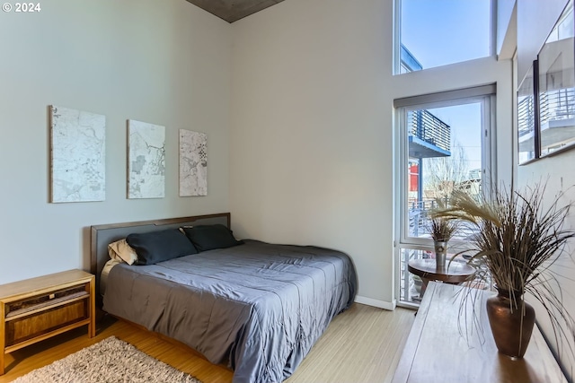 bedroom with a towering ceiling and light hardwood / wood-style floors