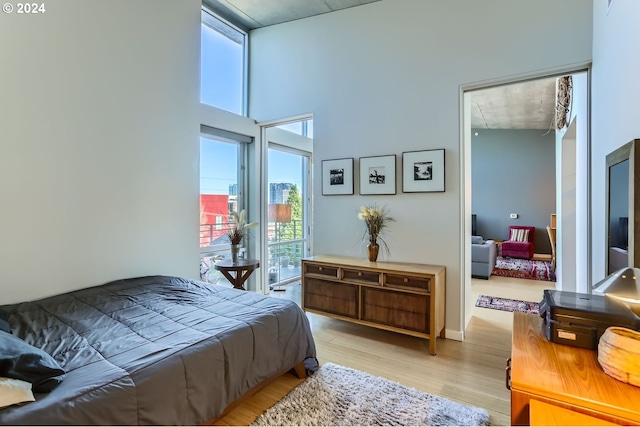 bedroom with light hardwood / wood-style floors and a towering ceiling