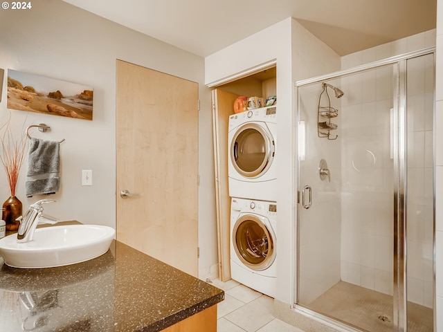 bathroom featuring sink, an enclosed shower, stacked washer and clothes dryer, and tile patterned flooring