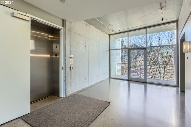 unfurnished room featuring elevator and concrete floors