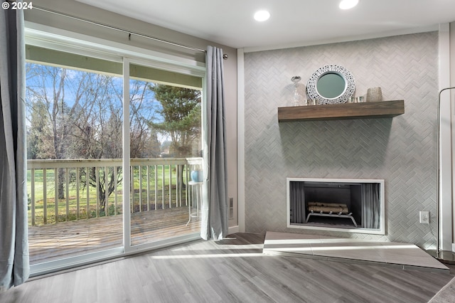 interior space featuring a tile fireplace, wood-type flooring, and a wealth of natural light