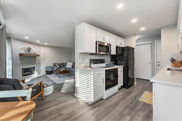 kitchen with black refrigerator, backsplash, white range with electric stovetop, hardwood / wood-style flooring, and white cabinetry