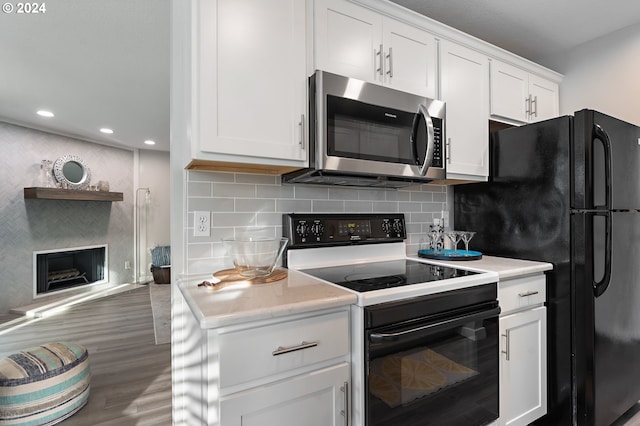 kitchen with dark hardwood / wood-style flooring, backsplash, black fridge, white electric range, and white cabinetry