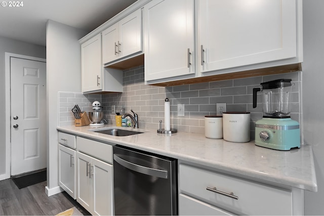 kitchen with light stone countertops, stainless steel dishwasher, sink, white cabinets, and dark hardwood / wood-style floors