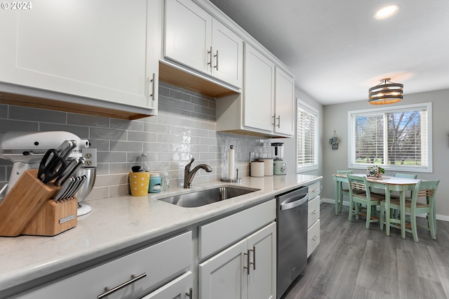 kitchen with dishwasher, white cabinets, sink, decorative backsplash, and wood-type flooring