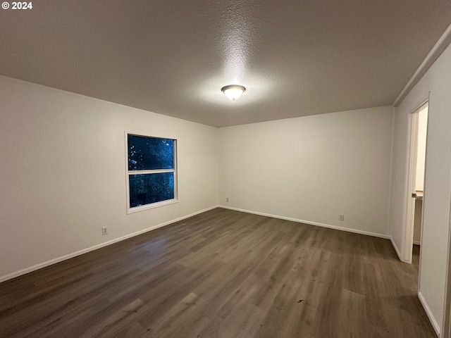 empty room with dark wood-type flooring and a textured ceiling