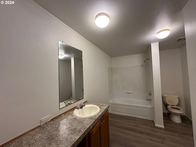 full bathroom with a textured ceiling, hardwood / wood-style flooring, toilet, vanity, and washtub / shower combination