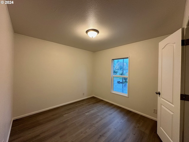 spare room featuring dark wood-type flooring and a textured ceiling