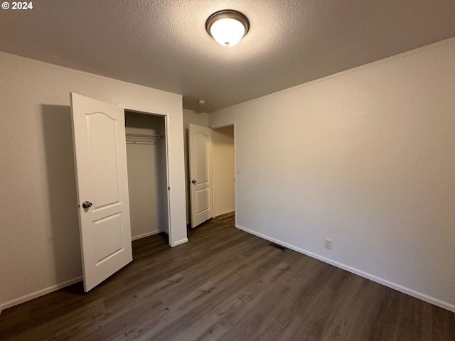 unfurnished bedroom featuring a closet, a textured ceiling, and dark hardwood / wood-style floors