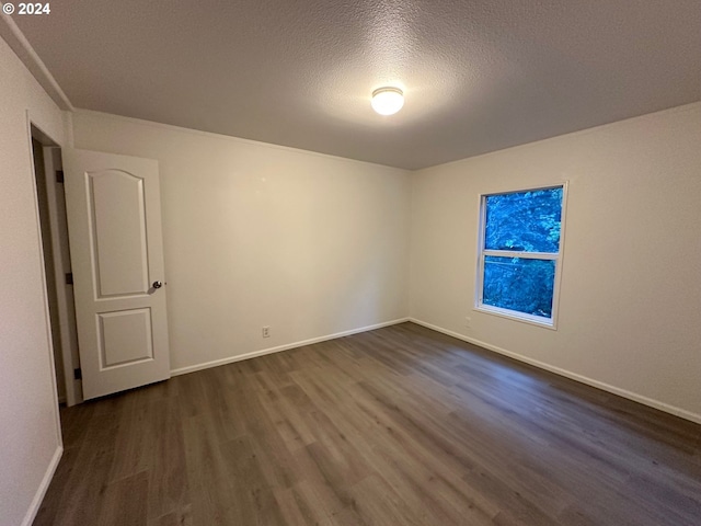 unfurnished room featuring dark wood-type flooring and a textured ceiling