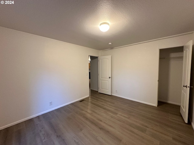 unfurnished bedroom featuring a textured ceiling, a closet, and dark hardwood / wood-style flooring