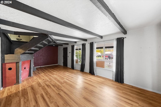 interior space featuring beam ceiling, wood-type flooring, and a textured ceiling