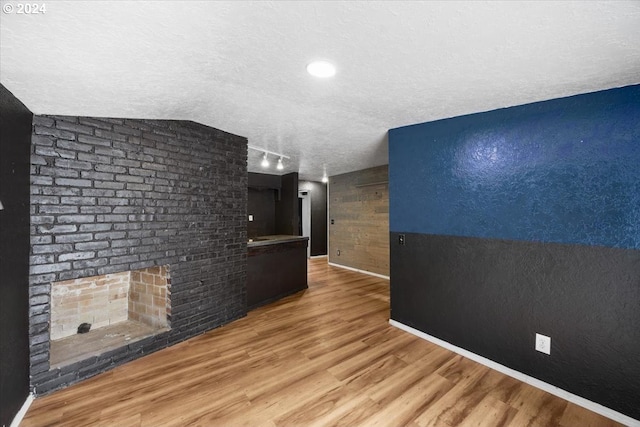 corridor with a textured ceiling, hardwood / wood-style floors, and vaulted ceiling