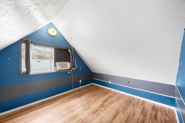 additional living space featuring wood-type flooring, a textured ceiling, and lofted ceiling