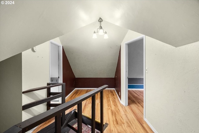 additional living space with light hardwood / wood-style floors, lofted ceiling, and a chandelier