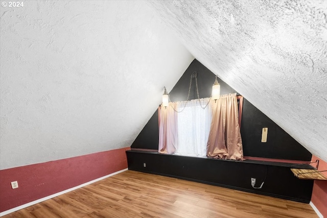 bonus room with a textured ceiling, wood-type flooring, and vaulted ceiling