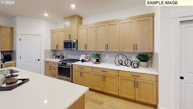 kitchen with light hardwood / wood-style floors, light brown cabinets, stainless steel appliances, and tasteful backsplash