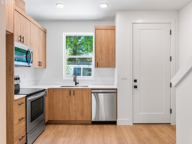 kitchen featuring light brown cabinetry, appliances with stainless steel finishes, sink, and light hardwood / wood-style flooring